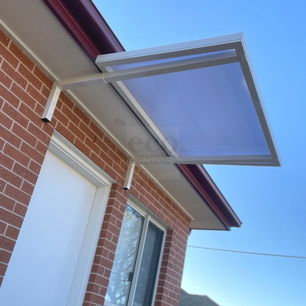 Slimline 50 aluminium door awning installed under the eave with wall-mounted brackets fixed to a brick wall and the awning starting at the fascia