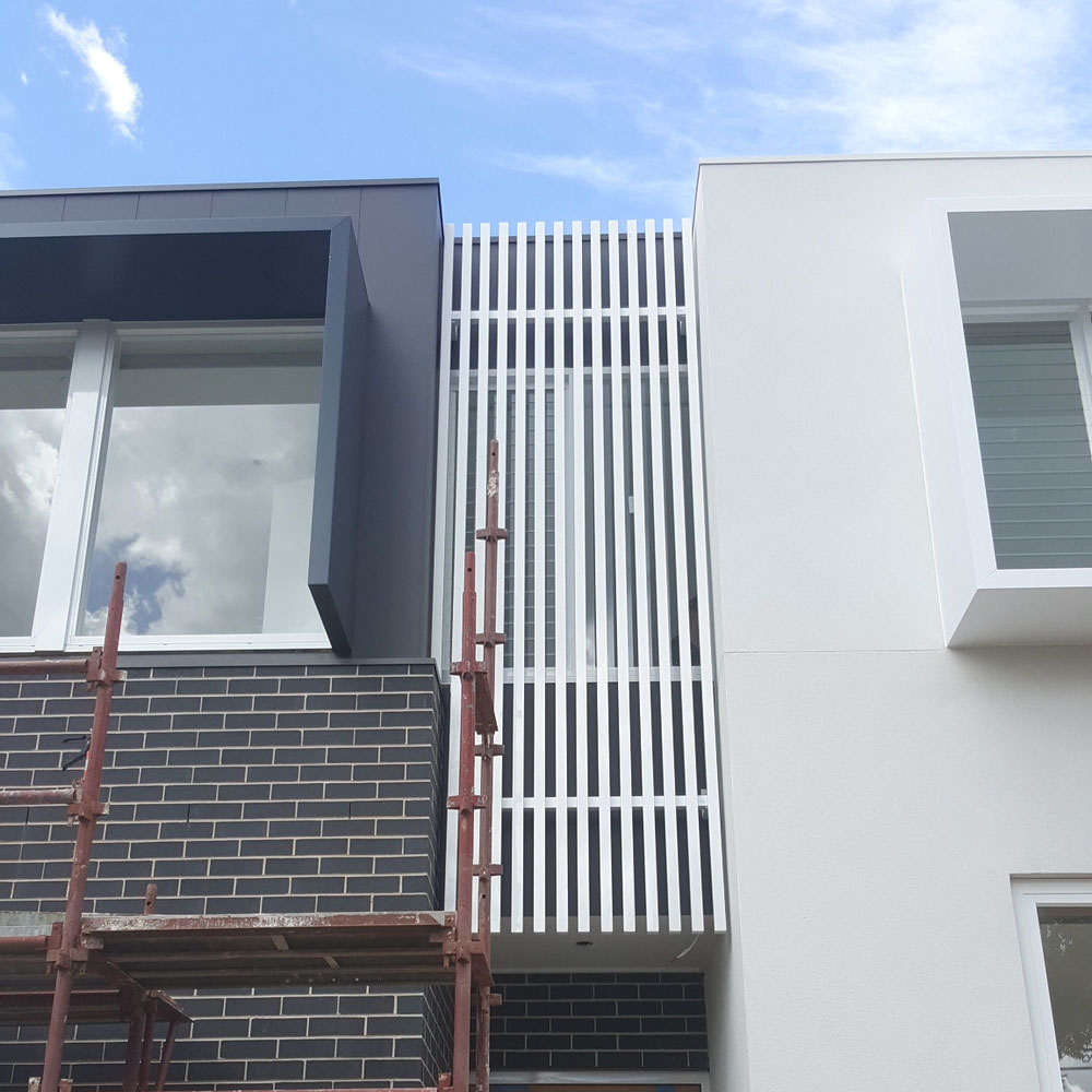 Custom vertical aluminium box-slat feature installed between two upper-storey facades for privacy and architectural styling.