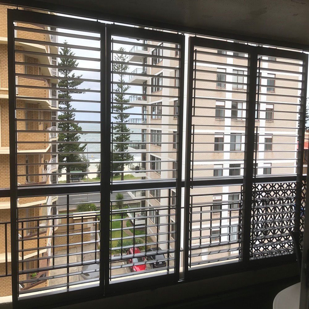 Adjustable aluminium louvres installed on a high-rise balcony, providing privacy while maintaining ocean views.