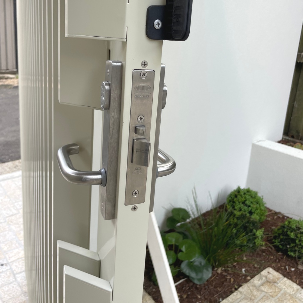 Stainless steel lock and handle detail on vertical angled aluminium slat gate