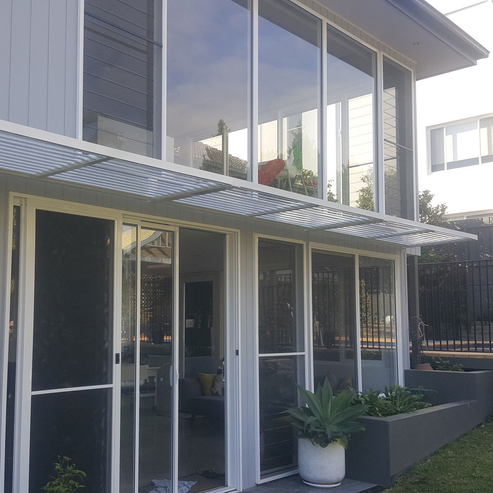 Cantilever aluminium louvre awning installed across large upper and lower windows on a modern two-storey home.