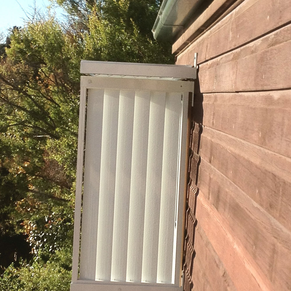 Vertical aluminium louvre privacy screen mounted to the side wall of a home.