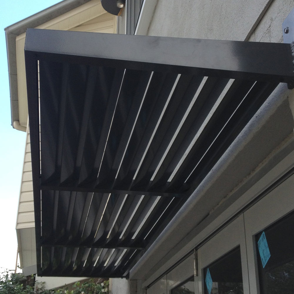 Black cantilever aluminium louvre awning installed above glass doors on a modern home.