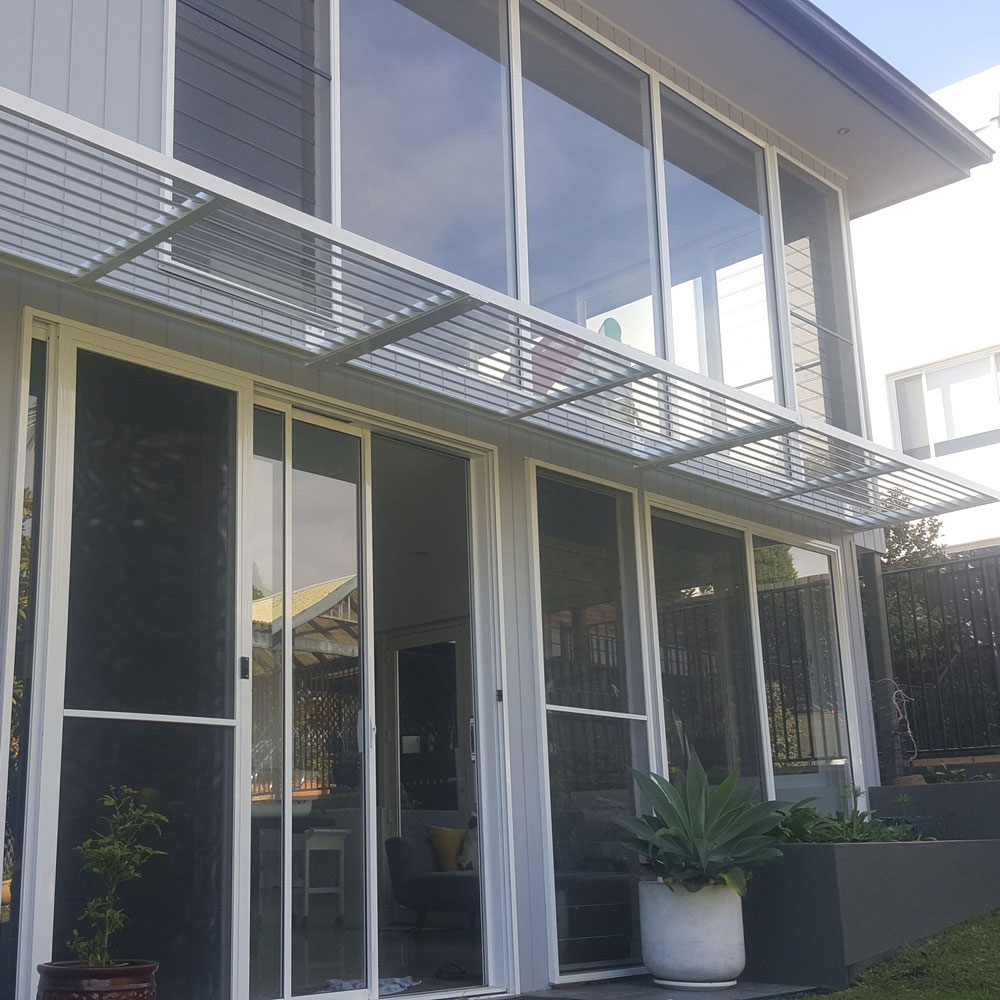 Cantilever aluminium louvre awning installed over sliding glass doors on the front façade of a modern two-storey home.