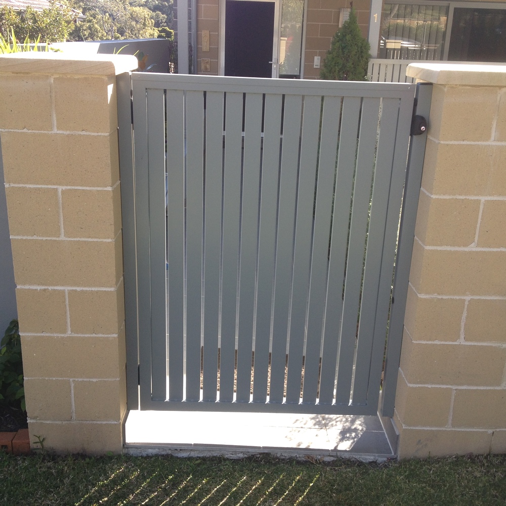 65mm vertical aluminium slat gate powder-coated in grey installed between rendered brick piers.