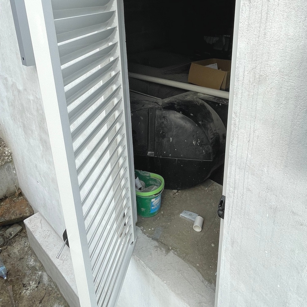 Aluminium louvre access door in open position showing the under-veranda storage area behind it.