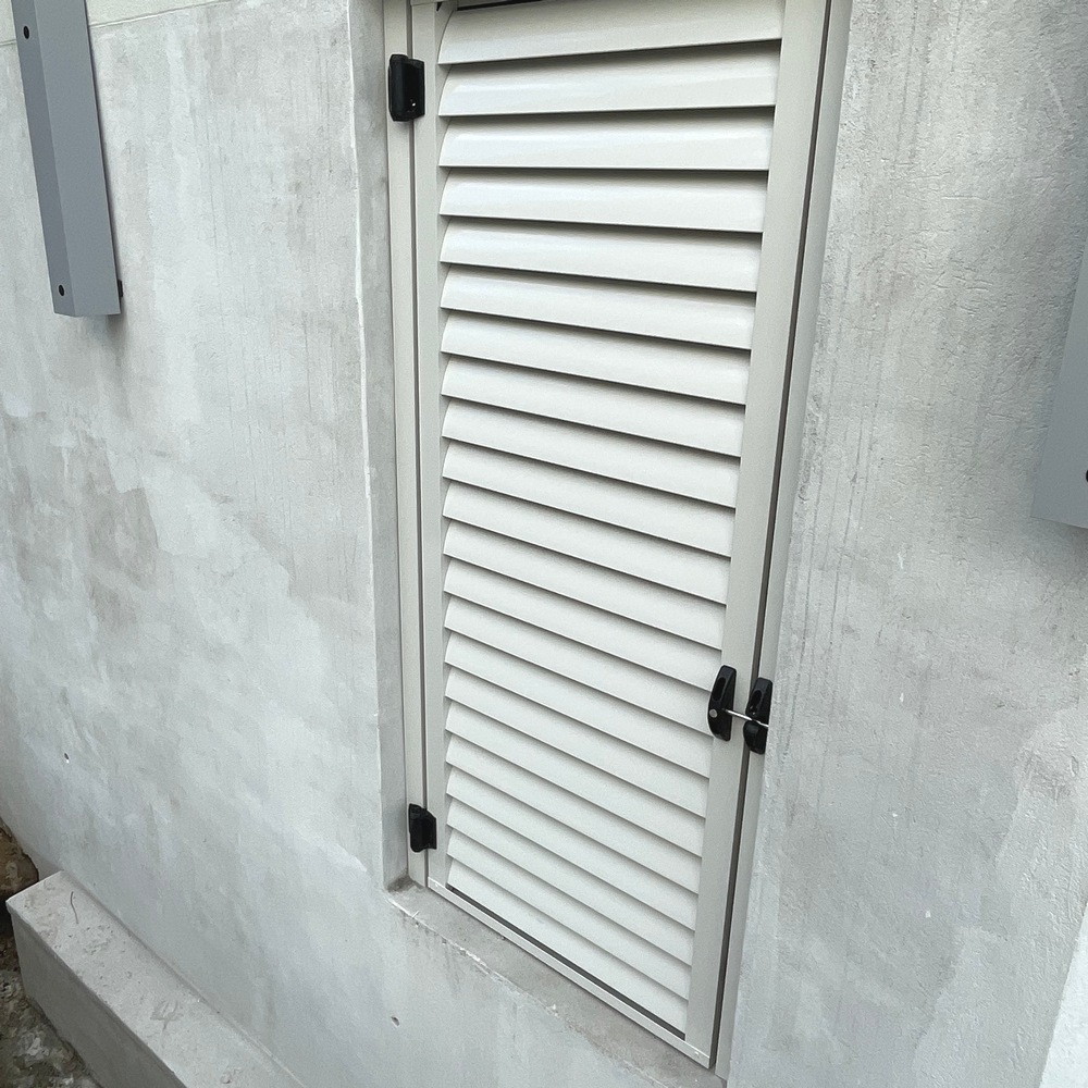Small aluminium louvre access door installed under a veranda for ventilation and secure entry.